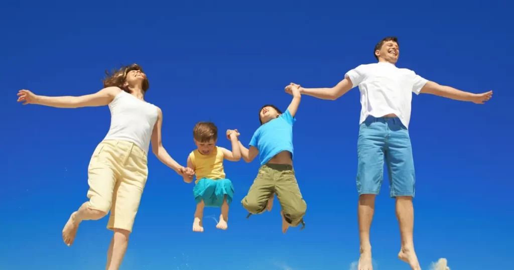 大空を背景に笑顔でジャンプする家族